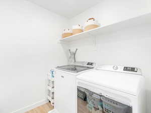 Laundry area with independent washer and dryer and light hardwood / wood-style flooring