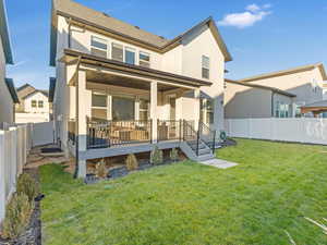 Back of house with a lawn and a deck