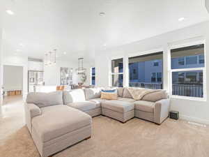 Carpeted living room with a chandelier