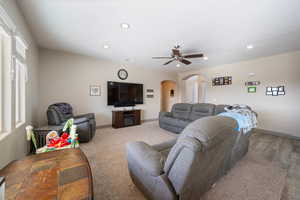 Living room featuring carpet flooring, ceiling fan, and a healthy amount of sunlight