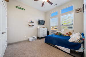 Carpeted bedroom featuring ceiling fan and a closet