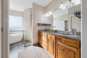 Bathroom featuring hardwood / wood-style flooring, vanity, decorative backsplash, and a bath