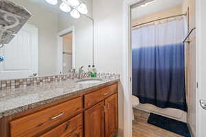 Full bathroom with vanity, backsplash, hardwood / wood-style flooring, toilet, and shower / bath combo with shower curtain