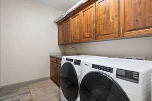 Laundry room featuring washer and clothes dryer, hardwood / wood-style floors, cabinets, and sink