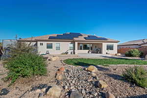 Rear view of property featuring a patio and solar panels