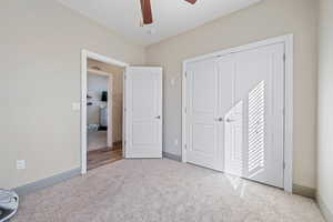 Unfurnished bedroom with light colored carpet and ceiling fan