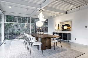 Dining space featuring beamed ceiling, expansive windows, and a wealth of natural light