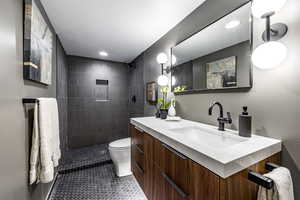 Bathroom featuring vanity, toilet, and tiled shower