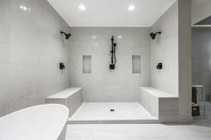 Bathroom featuring separate shower and tub and tile walls