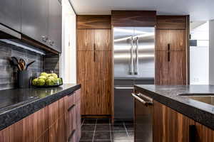 Kitchen featuring backsplash, dark tile patterned floors, and stainless steel appliances