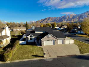 View of front of home with a mountain view, a garage, and a front lawn