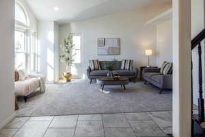 Carpeted living room featuring high vaulted ceiling