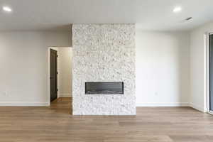 Interior details featuring a stone fireplace, a textured ceiling, and hardwood / wood-style flooring