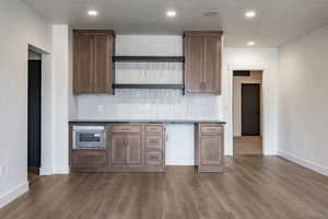 Kitchen featuring decorative backsplash, stainless steel oven, hardwood / wood-style floors, and a textured ceiling