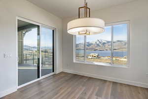 Unfurnished dining area featuring wood-type flooring, a wealth of natural light, and a water and mountain view