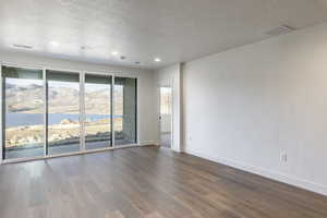 Unfurnished room featuring a water and mountain view, hardwood / wood-style floors, and a textured ceiling