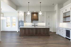 Kitchen with white cabinets, premium range hood, wine cooler, and dark hardwood / wood-style floors