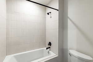 Bathroom featuring tiled shower / bath combo and toilet