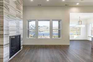 Unfurnished living room with a tile fireplace, dark hardwood / wood-style flooring, and a healthy amount of sunlight