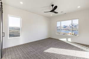 Spare room featuring a barn door, ceiling fan, and carpet