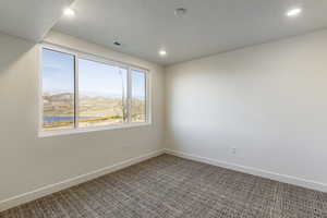 Empty room with carpet flooring, a mountain view, and a textured ceiling