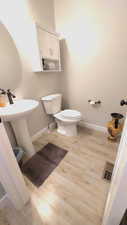 Bathroom with hardwood / wood-style flooring, toilet, and sink