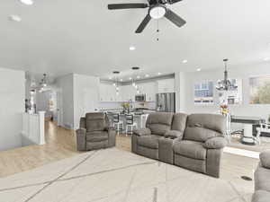 Family room, light hardwood / wood-style floors, and ceiling fan with notable chandelier