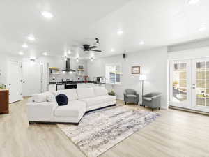 Living room featuring ceiling fan, light wood-type flooring, a textured ceiling, and french doors