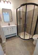 Bathroom with tile patterned flooring, vanity, toilet, and walk in shower