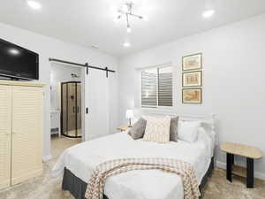 Bedroom featuring a barn door, a chandelier, and light colored carpet