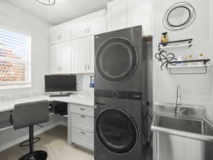 Laundry area featuring stacked washer / dryer, sink, and light tile patterned floors