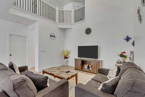 Living room with a towering ceiling and light hardwood / wood-style flooring