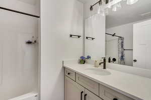 Bathroom featuring vanity, shower / bath combination with curtain, and a textured ceiling