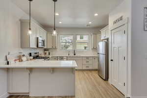 Kitchen with pendant lighting, a kitchen breakfast bar, sink, kitchen peninsula, and stainless steel appliances