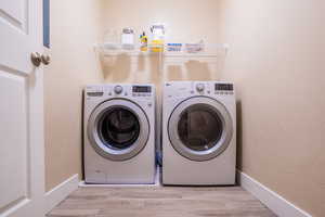 Laundry area with light hardwood / wood-style floors and separate washer and dryer