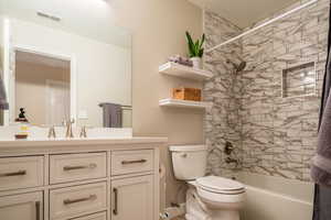 Full bathroom with vanity, toilet, and tiled shower / bath