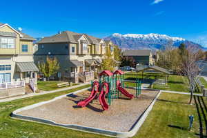 View of jungle gym with a mountain view and a lawn