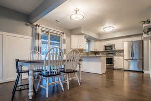 Kitchen with dark hardwood / wood-style flooring, white cabinets, stainless steel appliances, and a textured ceiling