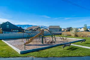 View of jungle gym with a mountain view and a yard