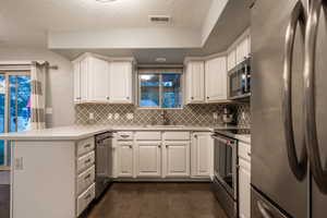 Kitchen with white cabinets, sink, dark hardwood / wood-style flooring, kitchen peninsula, and stainless steel appliances