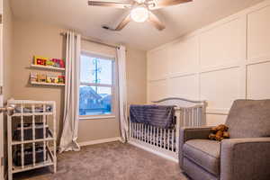 Bedroom with carpet flooring, ceiling fan, a textured ceiling, and a nursery area