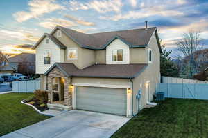 View of front of home featuring a yard, central AC unit, and a garage