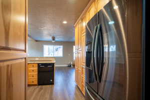 Kitchen with a textured ceiling, dishwasher, stainless steel fridge, and dark wood-type flooring