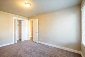 Unfurnished bedroom featuring a closet, carpet floors, and a textured ceiling