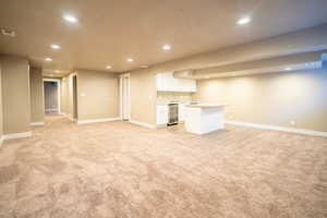 Basement open concept living room featuring  a fireplace and kitchen area.