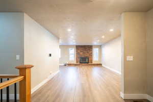 Unfurnished living room featuring a fireplace, light hardwood / wood-style flooring, and a textured ceiling