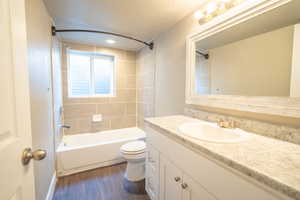 Full basement bathroom toilet, wood-style flooring, vanity, and tiled shower / bath