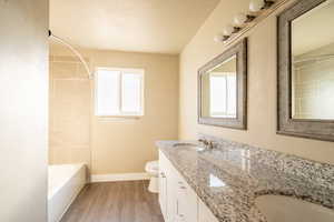 Full guest bathroom featuring  wood-style floors, vanity, tiled shower / bath.