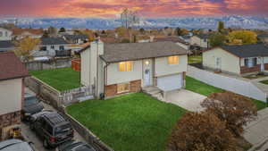 View of front of house featuring a mountain view, a garage, and a lawn