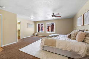 Bedroom with ceiling fan, carpet floors, and a textured ceiling